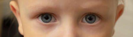 Close-up of a child with beautiful eyes. Curiosity, serious expression, fear, amazement, concentration conceptの写真素材