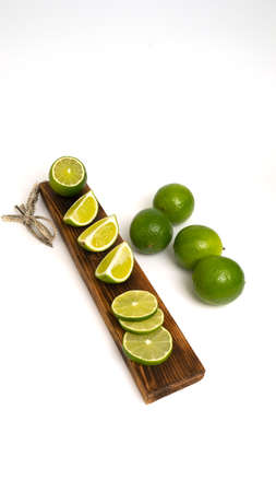 Sliced fresh lime on a wooden kitchen board on a white background. Preparation of the concept for...