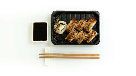 Sushi delivery box on a white background. Japanese menu in black transport box with chopsticksの写真素材