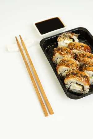 Sushi delivery box on a white background. Japanese menu in black transport box with chopsticksの写真素材