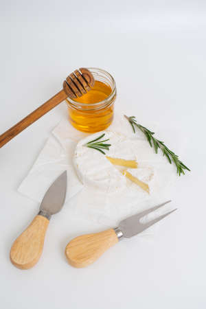 Round brie or camembert cheese on white plate with honey and rosemary sprigの写真素材