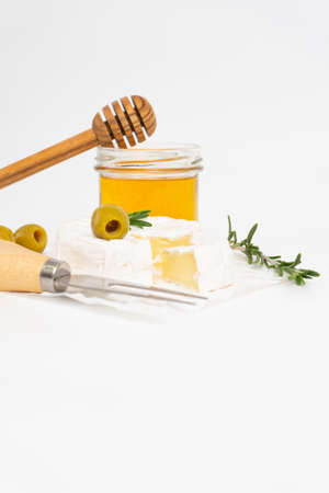 Round brie or camembert cheese on white plate with honey and rosemary sprigの写真素材