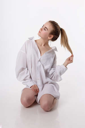 young female sitting on floor on knees. pretty girl with long hair in studioの写真素材