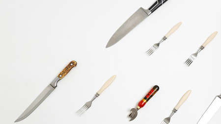 kitchen utensils: opener, forks, sharp knives isolated on white background. top view on group of tableware placed in diagonal pattern. simple flat lay composition with copyspace. Space for textの写真素材