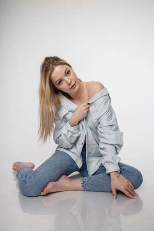 sexy caucasian girl posing in blue jeans and shirt on white studio backgroundの写真素材