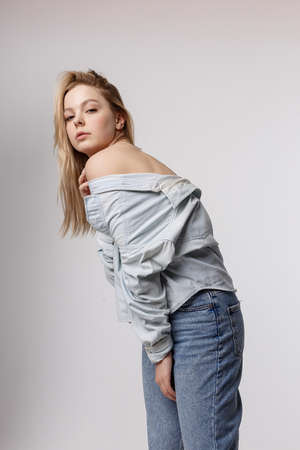 sexy caucasian girl posing in blue jeans and shirt on white studio backgroundの写真素材