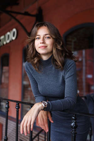 young thoughtful pretty girl in gray turtleneck, skirt with watches on armの写真素材