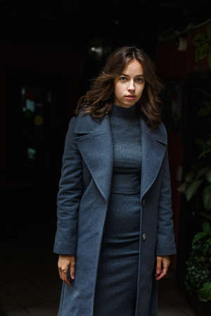 portrait of young thoughtful girl in gray coat and turtleneck posing outdoors
