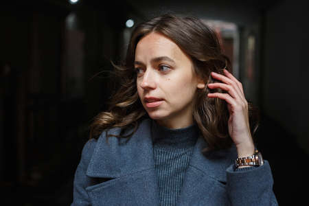 portrait of young thoughtful girl in gray coat and turtleneck posing outdoorsの写真素材