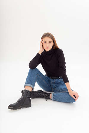 young caucasian woman in turtleneck and blue jeans isolated on white backgroundの写真素材