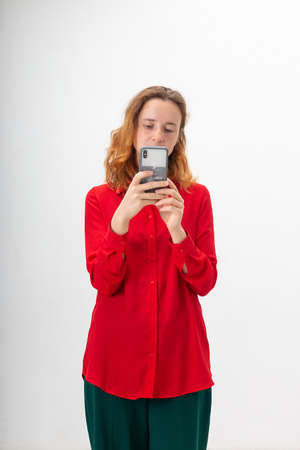young concentrated caucasian redheaded pretty woman with long hair in red shirt isolated on white...