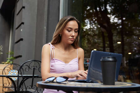 beautiful young asian business woman with dark long hair, sitting outdoors, working with laptop....