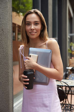 beautiful young asian woman with dark long hair, standing outdoors with laptop, having rest. pretty...