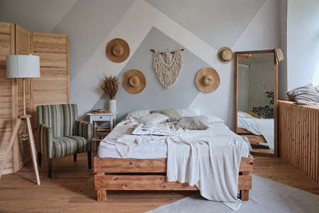 stylish bright loft cozy living room with double bed, armchair, night lamp, carpet, houseplant,...