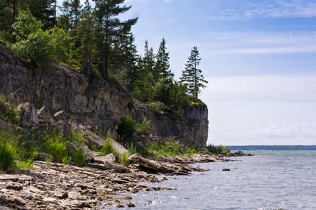 Limestone cliff in the sea under blue sky and white cloudsの写真素材