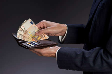 Businessman hands holding wallet with credit cards and stack of money, euro bills. Fifty euros...