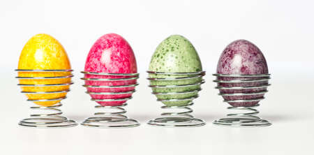Multicolored chicken eggs in egg holder. Green, red, yellow, purple egg in metal eggs holderの写真素材