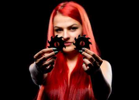 Portrait of beautiful girl with circular saw blade. Bretty naked woman, long red hair,  nude body, sawblade, dark background. Female and sharp stainless steel discの写真素材