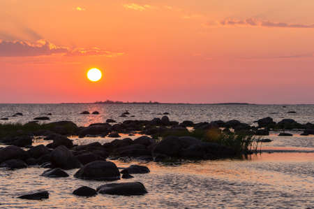 Sunset rocky beach, peaceful sea, orange sky. Kihnu, small island in Estonia. Baltic sea, Europe. Natural environment background.の写真素材