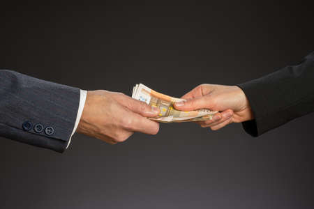 Business people hands and fifty euros banknotes, isolated gray background. Give a money, bribe. Corruption concept. Man and woman handの写真素材