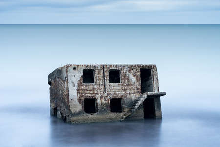 Liepaja beach bunker. Brick house, soft water, waves and rocks. Abandoned military ruins facilities in a stormy sea. Barracks building in the Baltic sea.  Liepaja, Latvia, Europe.の写真素材