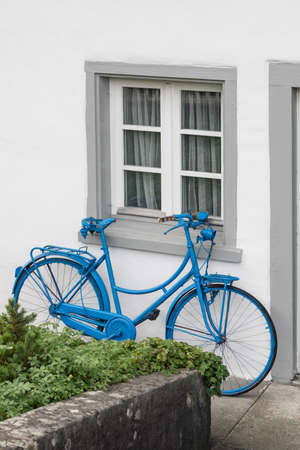 The decoration of vintage bicycle and white building with green door. Old blue retro bike and holiday house background.の写真素材