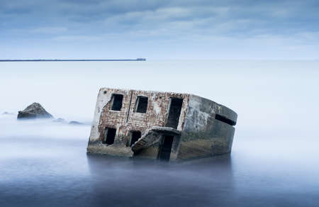 Liepaja beach bunker. Brick house, soft water, waves and rocks. Abandoned military ruins facilities in a stormy sea. Barracks building in the Baltic sea.  Liepaja, Latvia, Europe.の写真素材