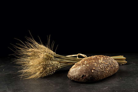 Rye bunch and bread on dark wooden table,  isolated on black background. Food, bakery conceptの写真素材