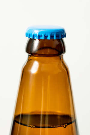 Brown glass bottle and blue cap, white background.の写真素材