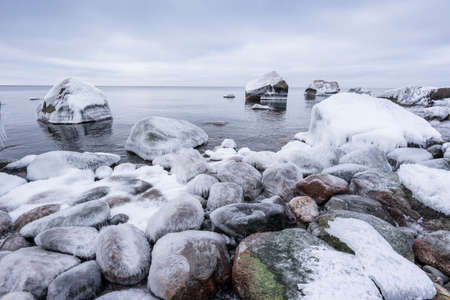 Rocky beach on wintertime. Evening light and icy weather on shore like fairy tale country. Winter on coast. Blue sky, white snow, ice covers the land on seaside. Waterside on Juminda, Estonia, Europeの写真素材