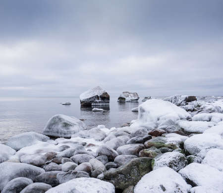 Rocky beach on wintertime. Evening light and icy weather on shore like fairy tale country. Winter on coast. Blue sky, white snow, ice covers the land on seaside. Waterside on Juminda, Estonia, Europeの写真素材