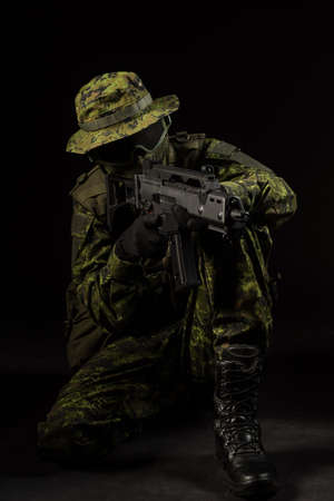 Portrait of armed woman with camouflage. Young female airsoft sniper observe with firearm. Soldier with gun in war, black background.  Military, army people conceptの写真素材