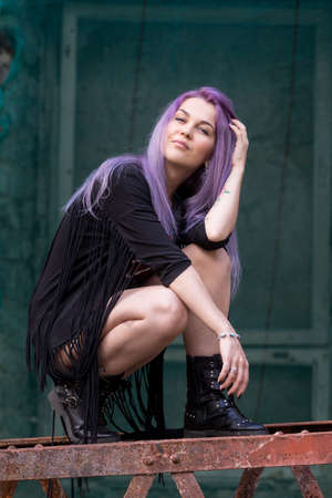 Caucasian white female model and brick stone in the city, modern fashion concept. Woman climbs on an old rust ladder, limestone walls background.の写真素材
