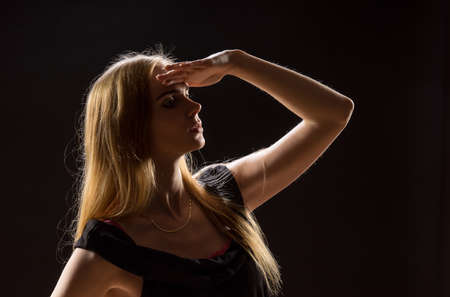 Young woman waving her hands. Blonde girl  expressing with raised hands their emotions in a studio on a black backgroundの写真素材
