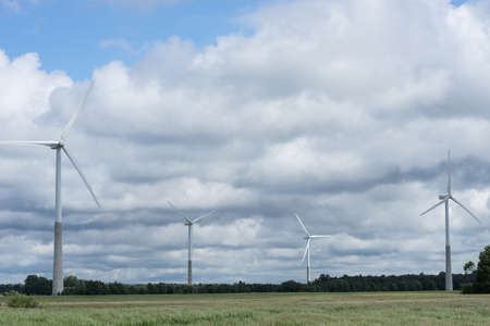 Ecology concept: Blue sky, white clouds, wind turbine and crop field. Wind generator for...