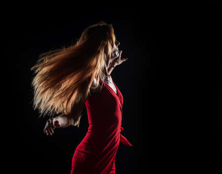 Caucasian white female model portrait. The wind blowing the long blonde hair off on beautiful girl. Woman posing studio shot on a black backgroundの写真素材