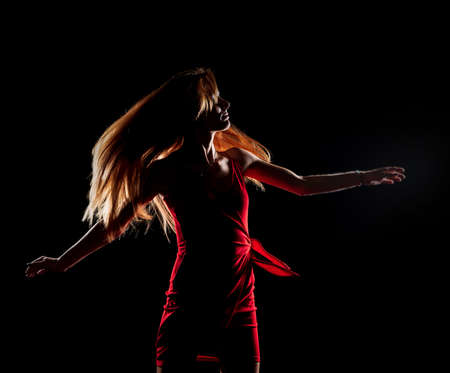 Caucasian white female model portrait. The wind blowing the long blonde hair off on beautiful girl. Woman posing studio shot on a black backgroundの写真素材