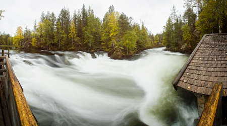 Cliff, stone wall, forest, waterfall and wild river panoramic view in autumn. Fall colors - ruska time in Myllykoski. Karhunkierros Trail, Oulanka National Park in north Finland. Lapland, Europeの写真素材