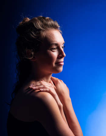 Beautiful woman with brunette long curly hair. Beauty portrait of modern fashion, blue background.の写真素材
