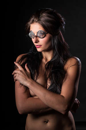 Young nude woman with make up. Model with glasses. Naked girl beauty portrait on black background.の写真素材