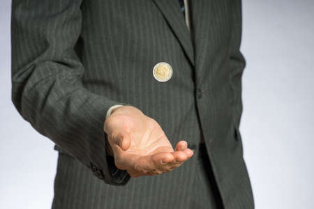 Business man with gray jacket throws up a euro coin. European finance currency. の写真素材