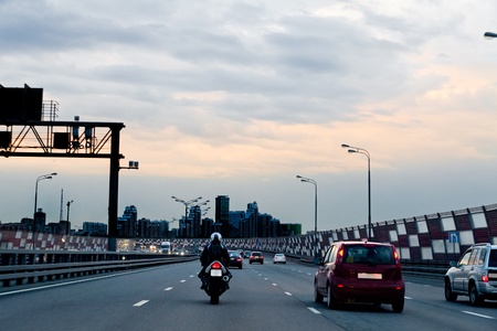 Car and motorcycle on the highway-evening. The urban landscape.
