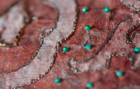 Embroidery and green pearls on dusty orange organza textileの写真素材