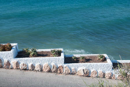 Planting pots going  downwards  on a walking path by the Mediterranean sea  の写真素材
