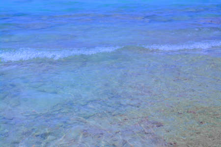 Deep blue and transparent water with small wave softly foaming ashore 