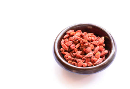 Goji Berries in dark brown ceramic bowl isolated on white