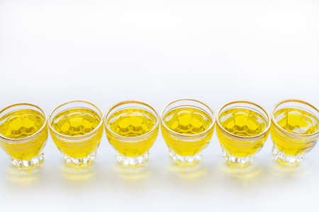 Six small shot glasses in a row with golden olive oil and white copy space の写真素材