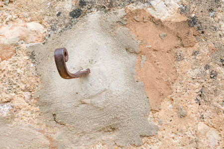 Rusty hook to the right on plastered wall with grungy look and warm earthy colorsの写真素材