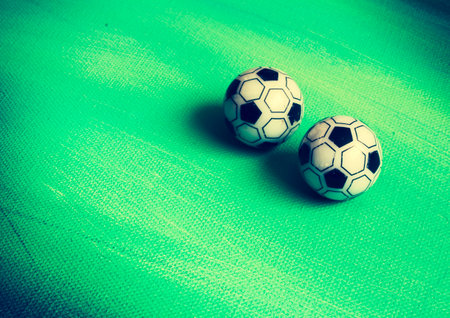 Two toy soccer balls on green canvas