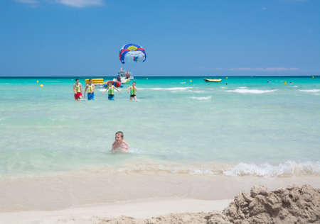 Happy vacation kids in different ages on Playa de Muro beach with emerald crystal clear water and sports activities  Playa de Muro, Mallorca, Balearic islands, Spain のeditorial素材